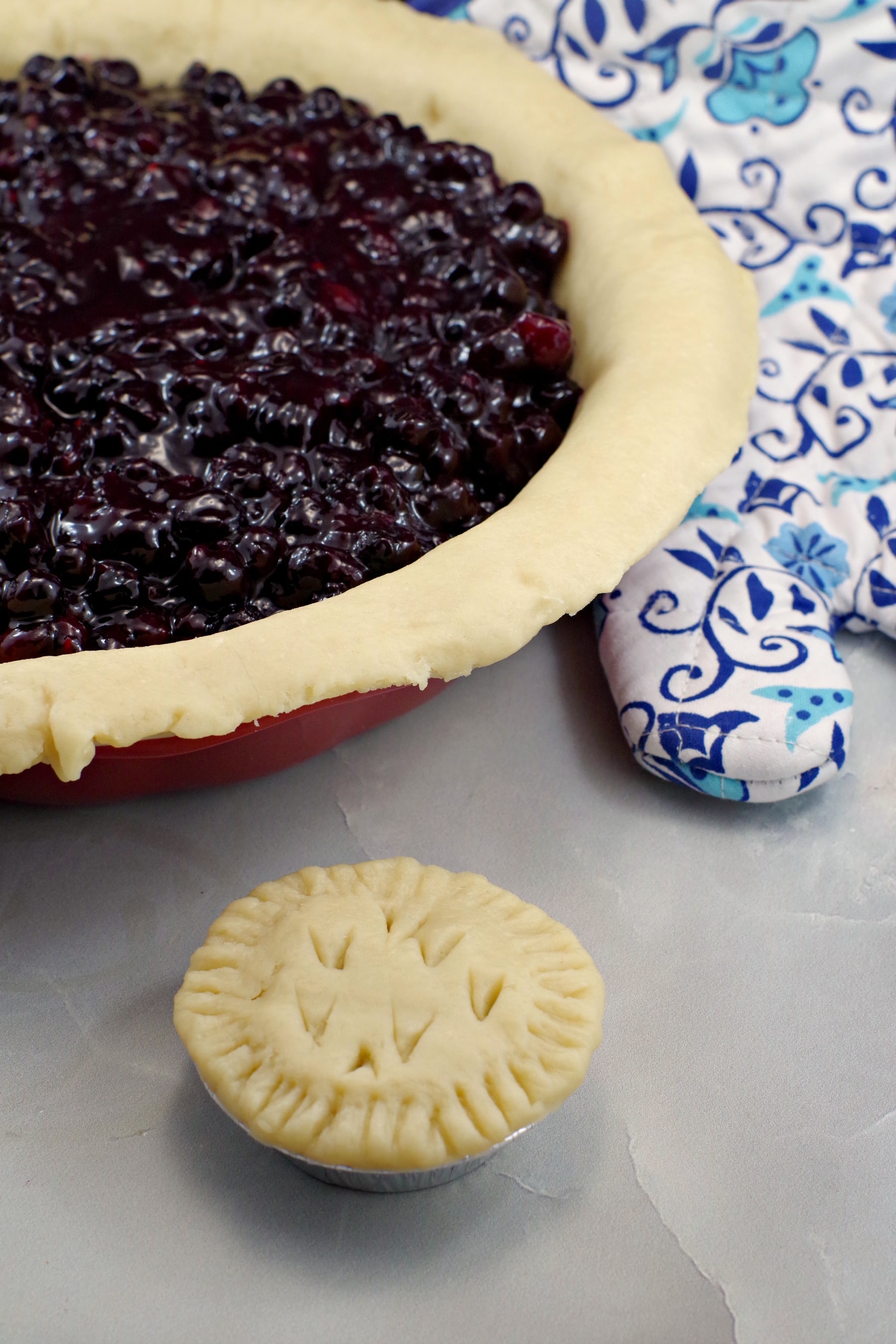 Never fail pie crust with filling with tart in front and blue patterned oven mitt in the background