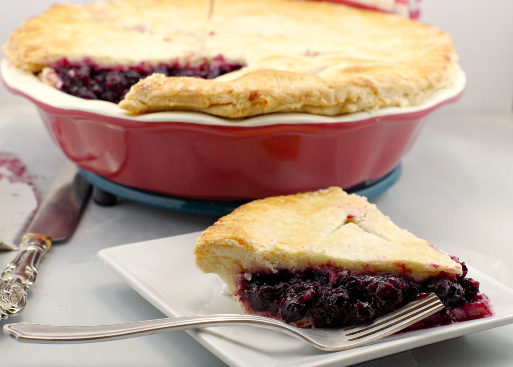 Saskatoon berry pie on plate with whole pie in background