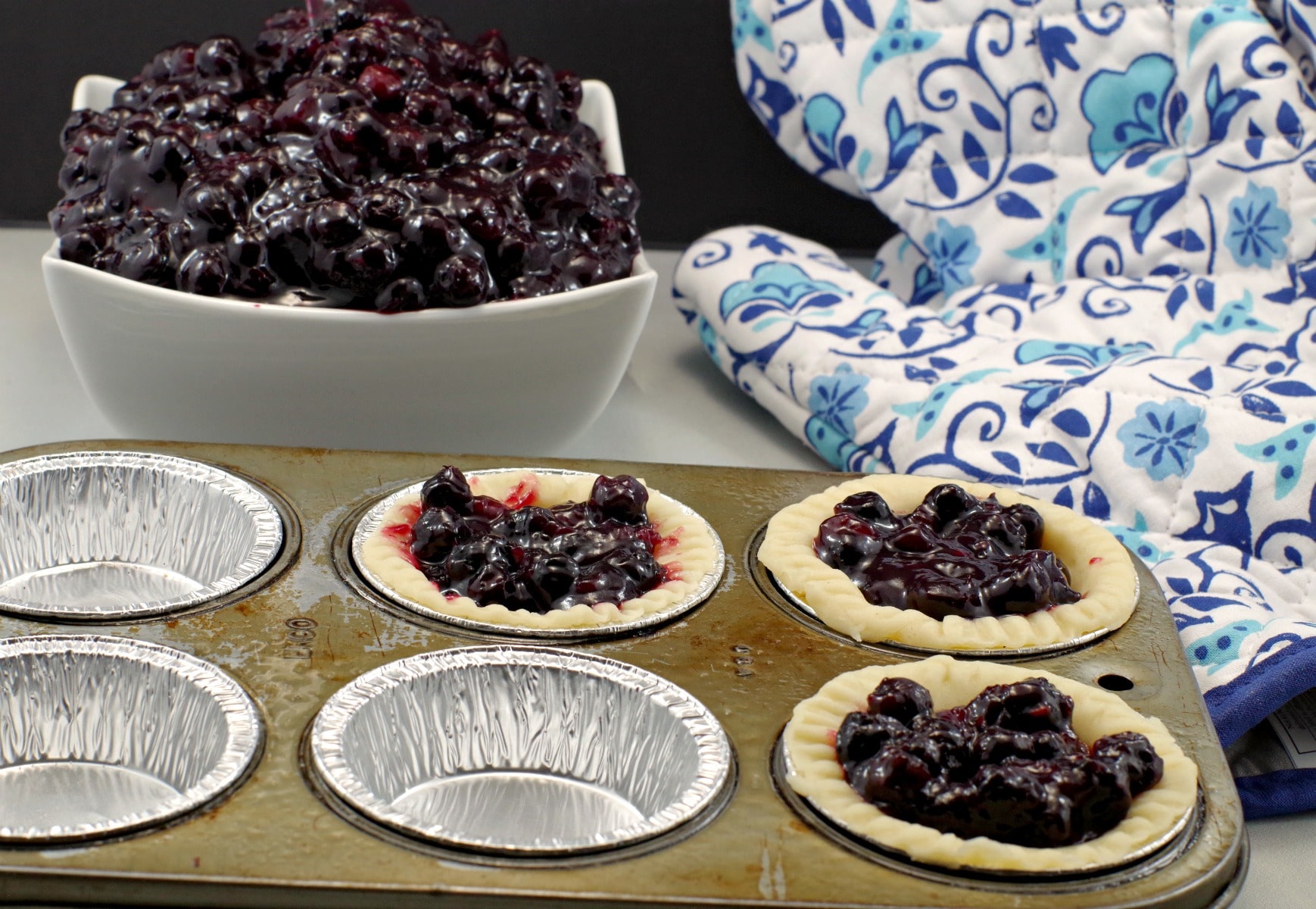 Saskatoon berry pie filling in tarts with bowl of pie filling in background