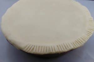 pie crust edges being pleated with a fork