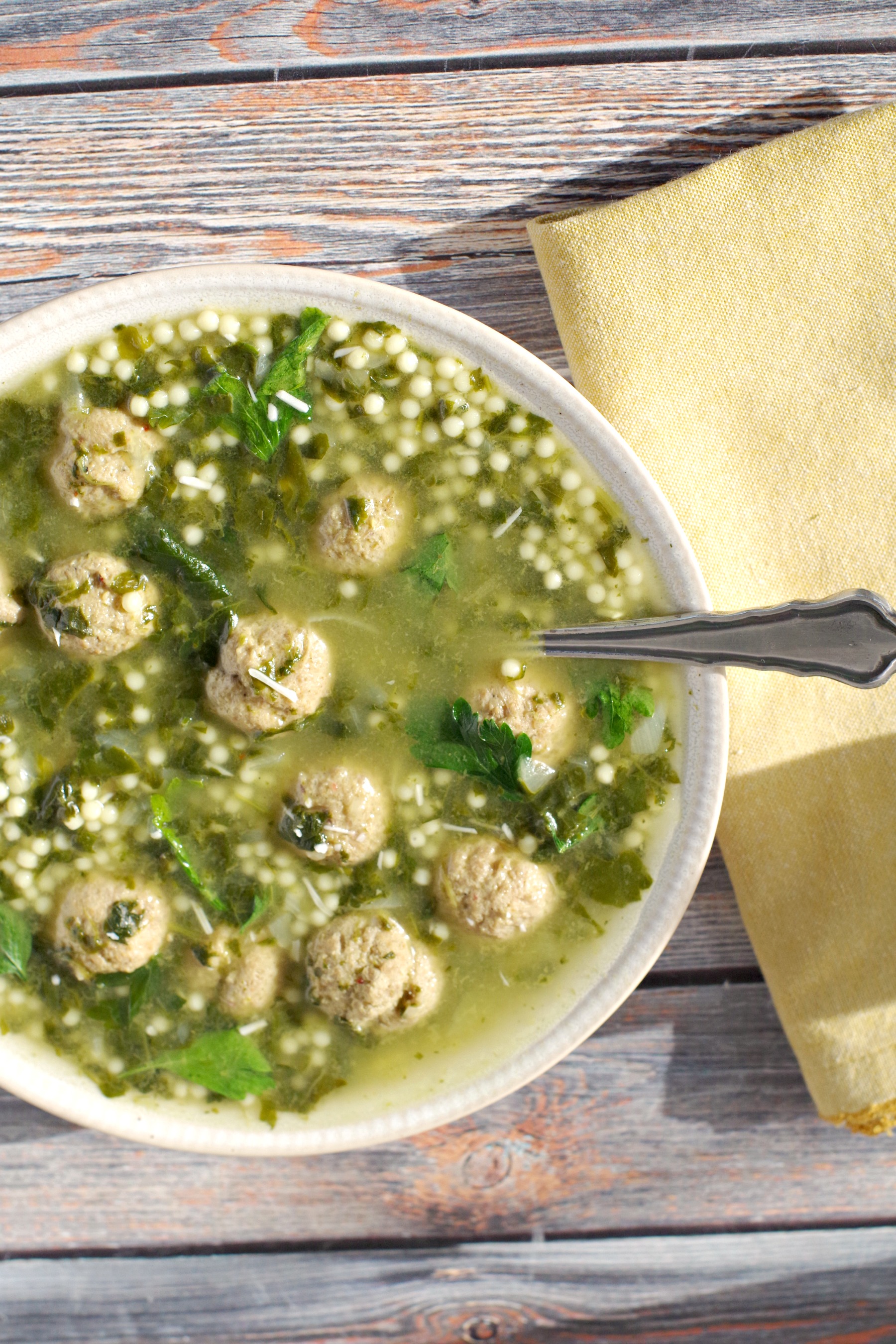 Bowl of Easy Italian Wedding soup with spoon and yellow napkin
