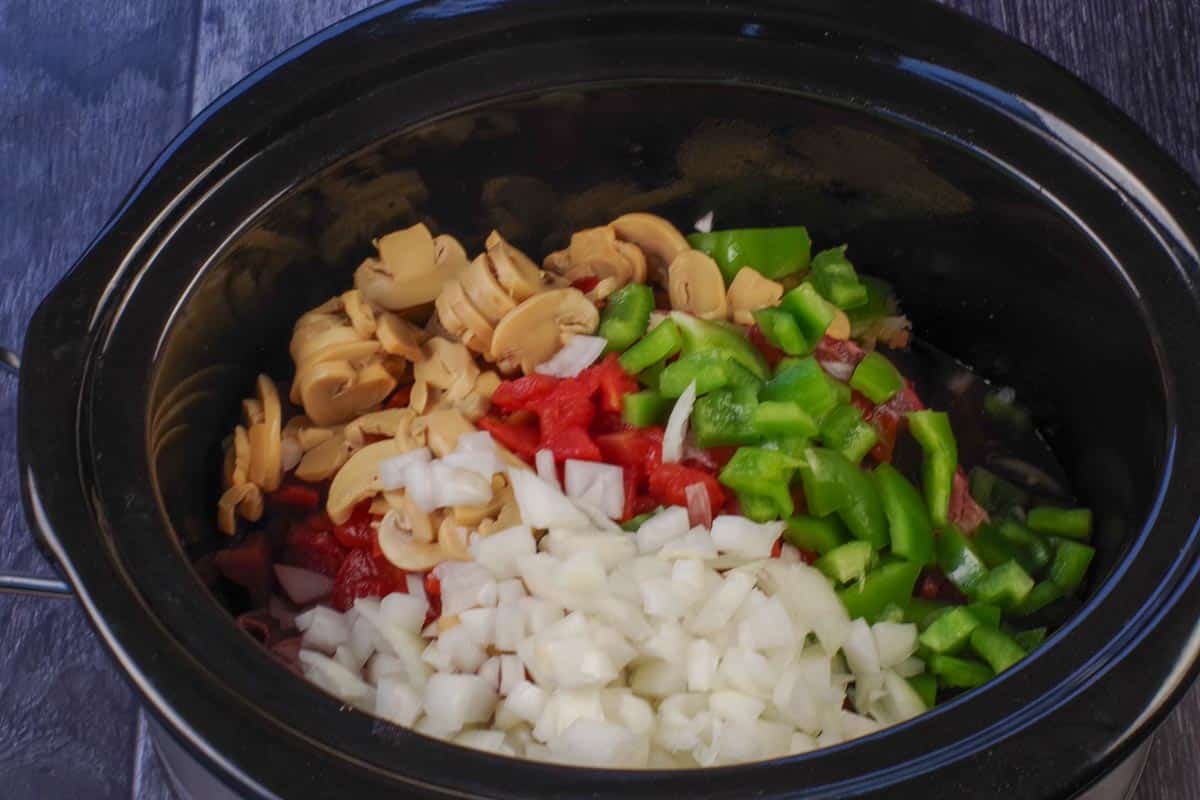 onion, diced tomatoes, green pepper and garlic added over steak in slow cooker