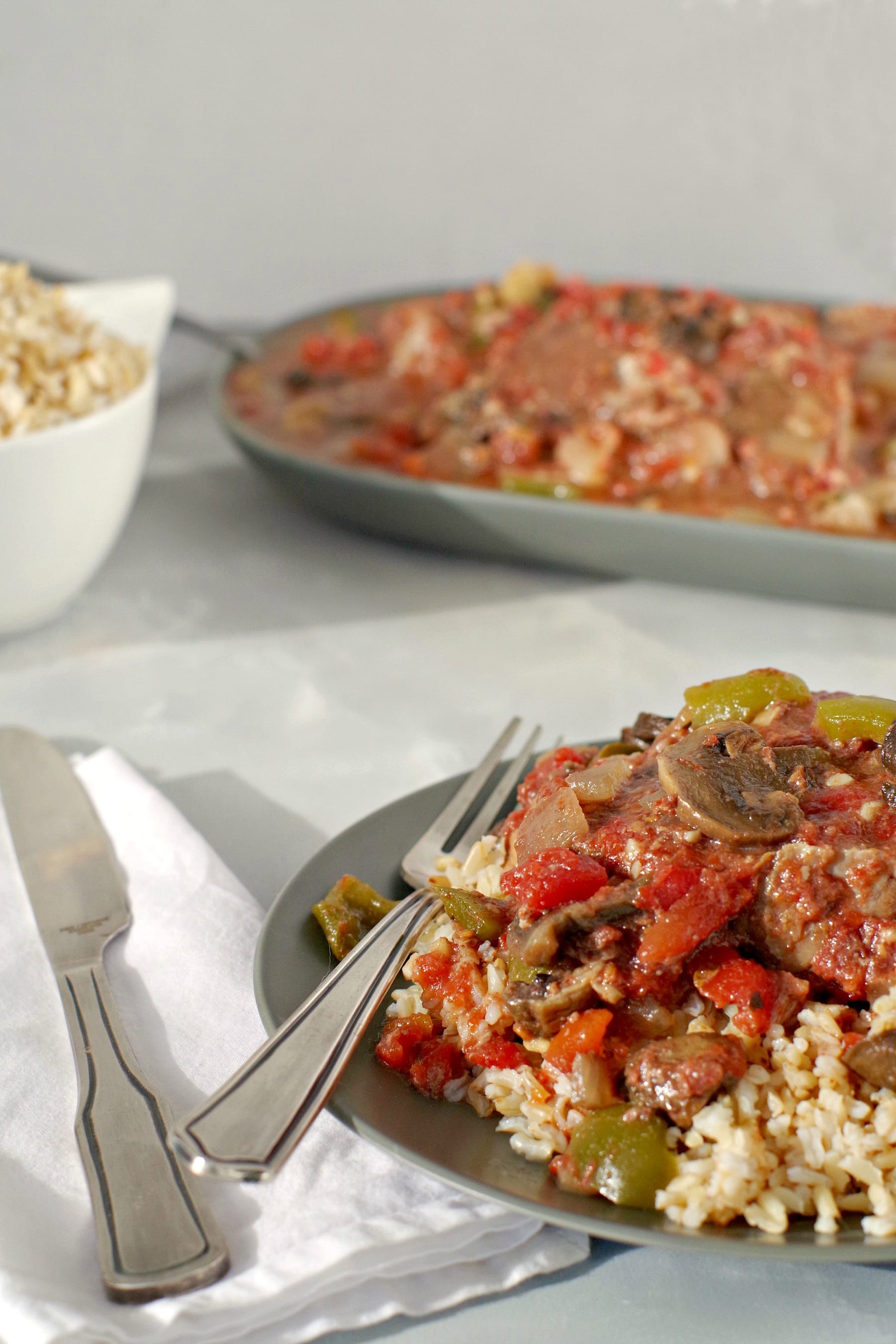 swiss steak shown topped with vegetables over rice