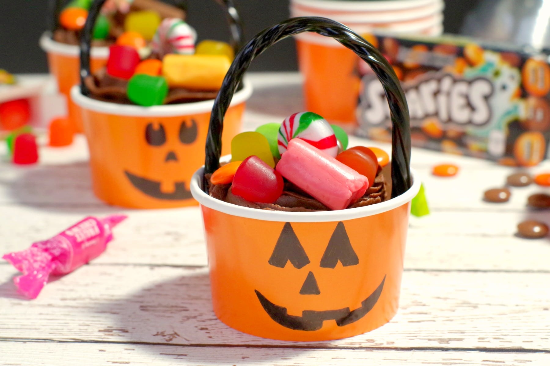 Halloween Jack o'latern bucket cupcake with candy strewn around