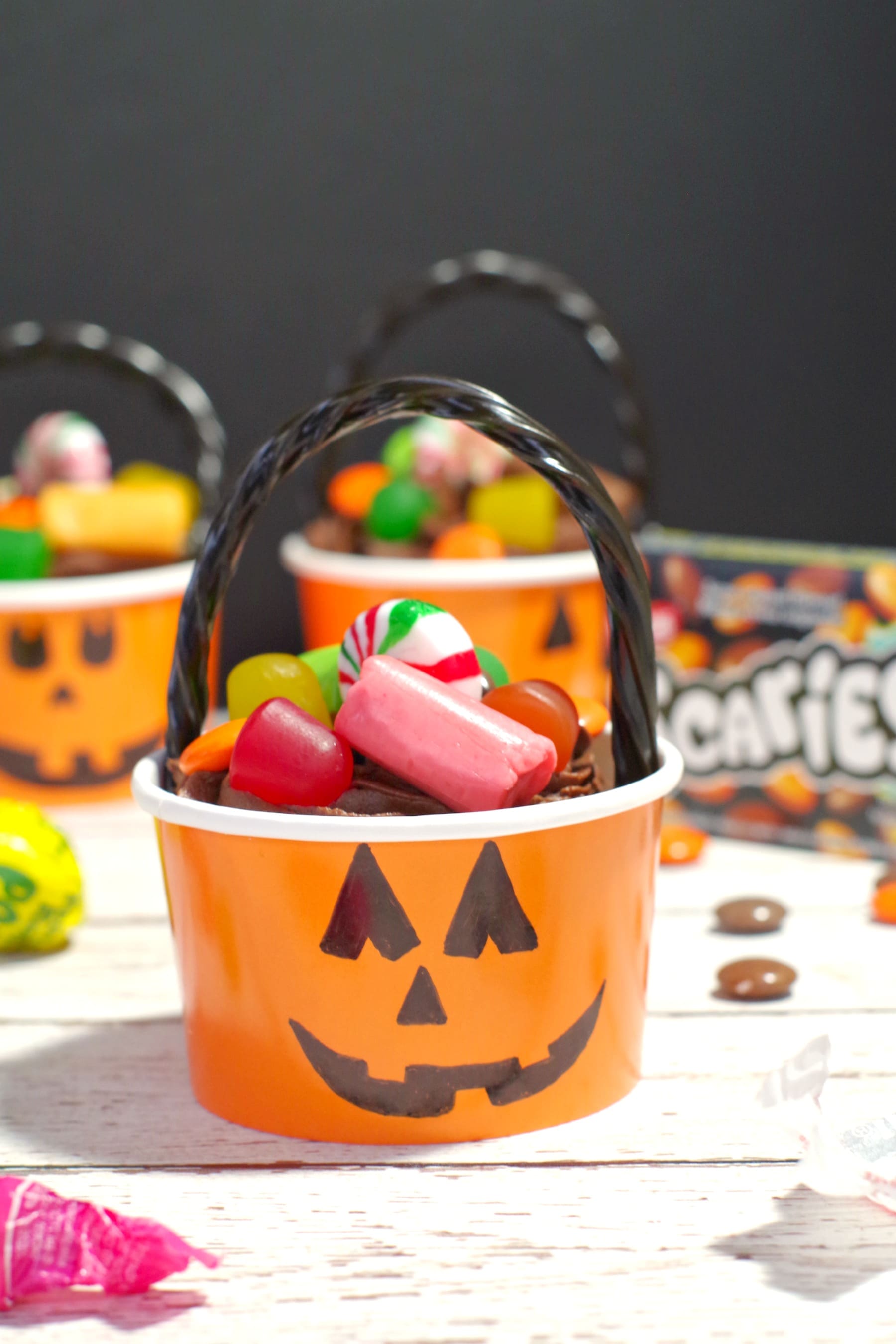 Halloween Jack o'latern bucket cupcake with candy strewn around