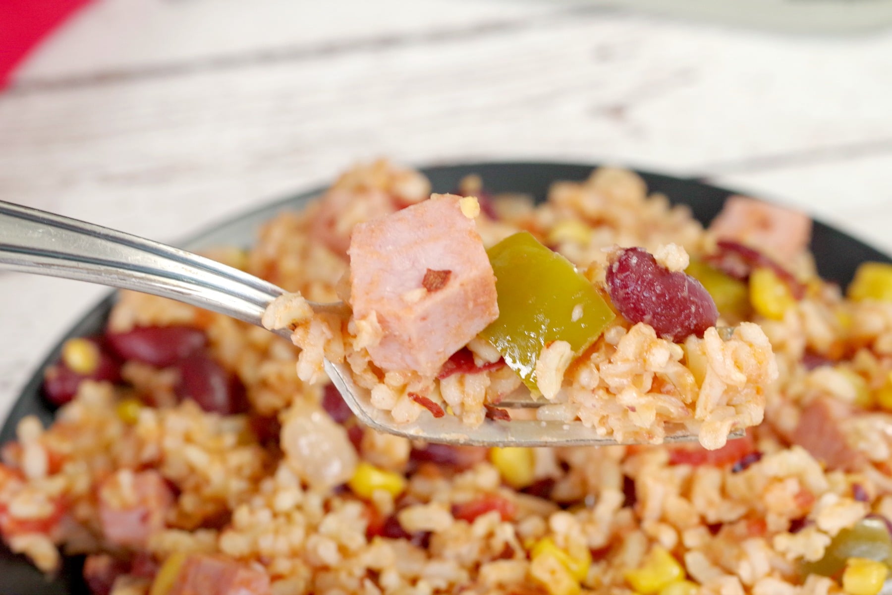 Leftover Ham, Rice and Beans being held on a fork with plate of it in the background