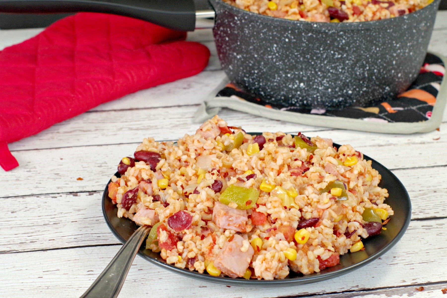 Leftover Ham, Rice and Beans on black plate, with black and white speckled pot in background