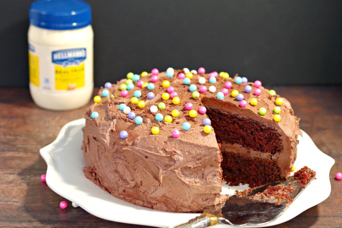 Chocolate Mayonnaise Cake with a slice missing and a jar of mayonnaise in the background.