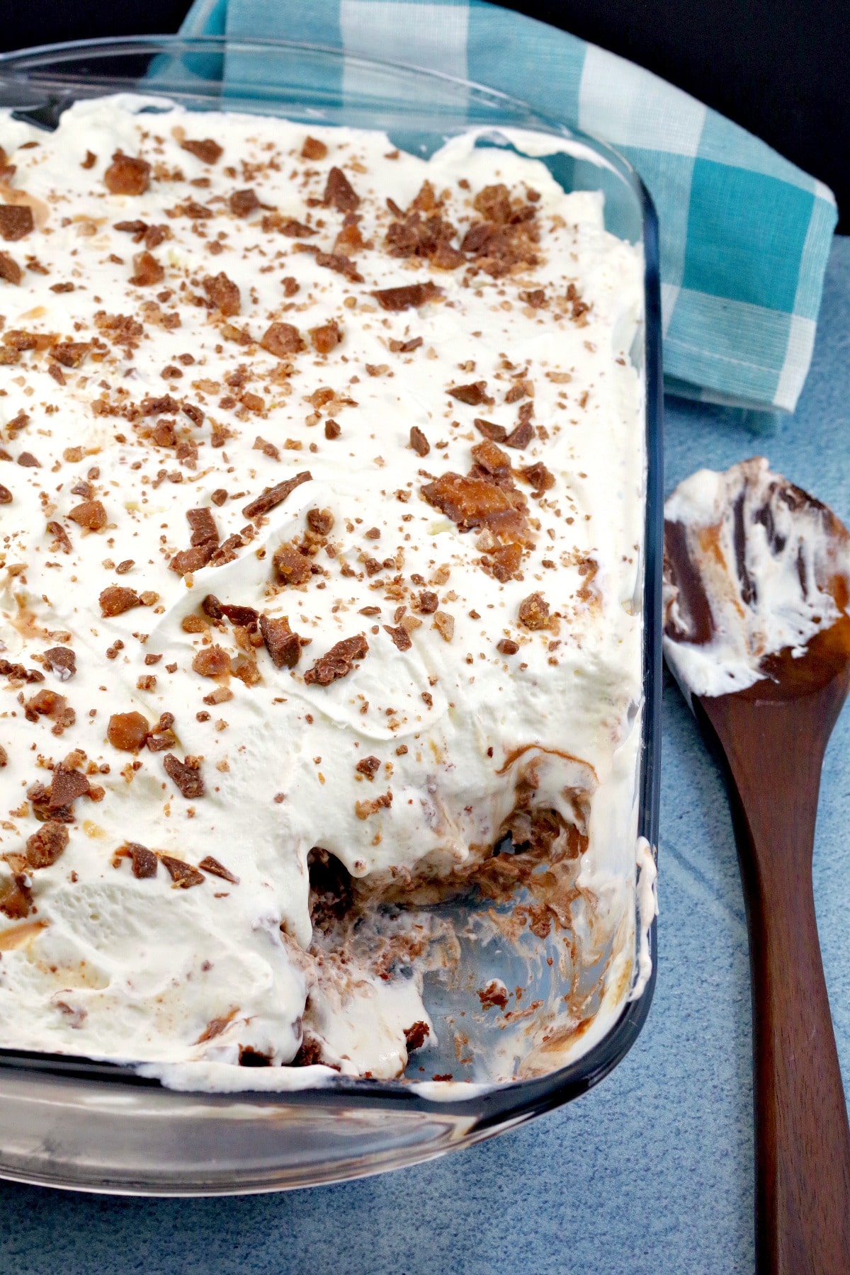 Skor bar dessert recipe in 9X13 glass pan, with some removed and wooden spoon to the right side