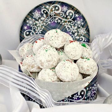 Almond Snowball cookies in a blue Christmas cookie tin, with ribbon around it