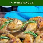 Cooked Cornish Hens in wine sauce in a glass pan, garnished with fresh rosemary.