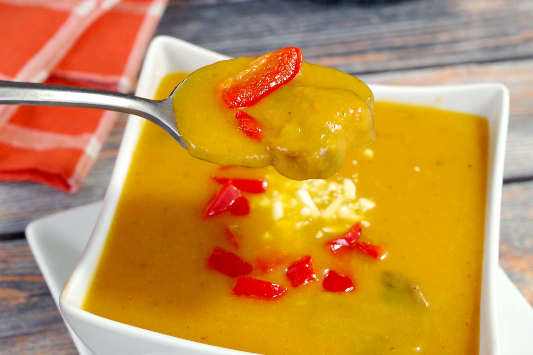 Pumpkin soup being held up on a spoon over bowl