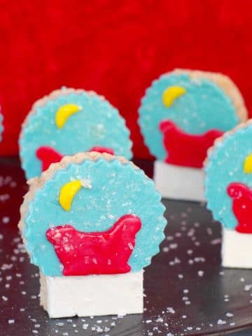snow globe rice krispie treats on a black platter with red background