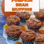 apricot bran pumpkin muffins on a white cake platter with apricots and a pumpkin in the background