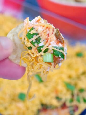 tortilla chip being dipped into cold nacho dip