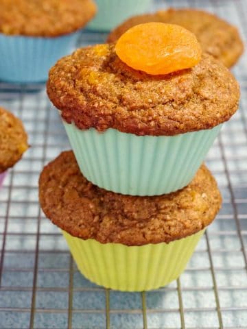 2 pumpkin bran muffins stacked on top of each other on a cooling rack