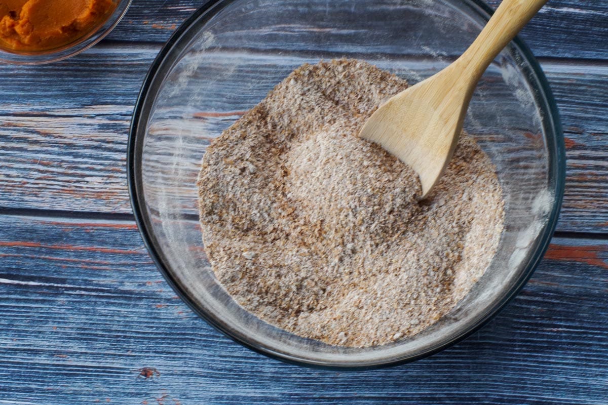 dry ingredients in a glass bowl with a woodden spoon