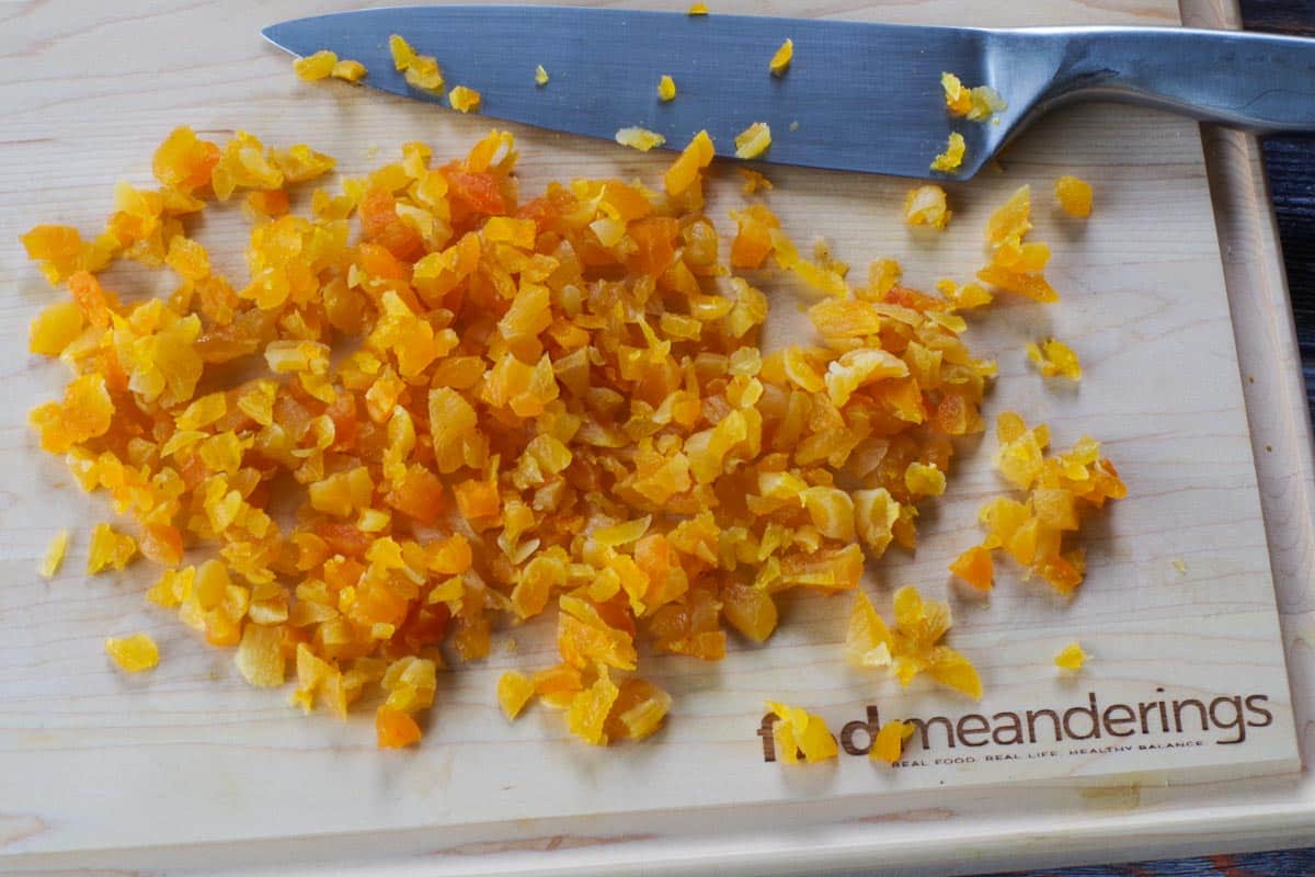 chopped apricots on wooden cutting board with knife