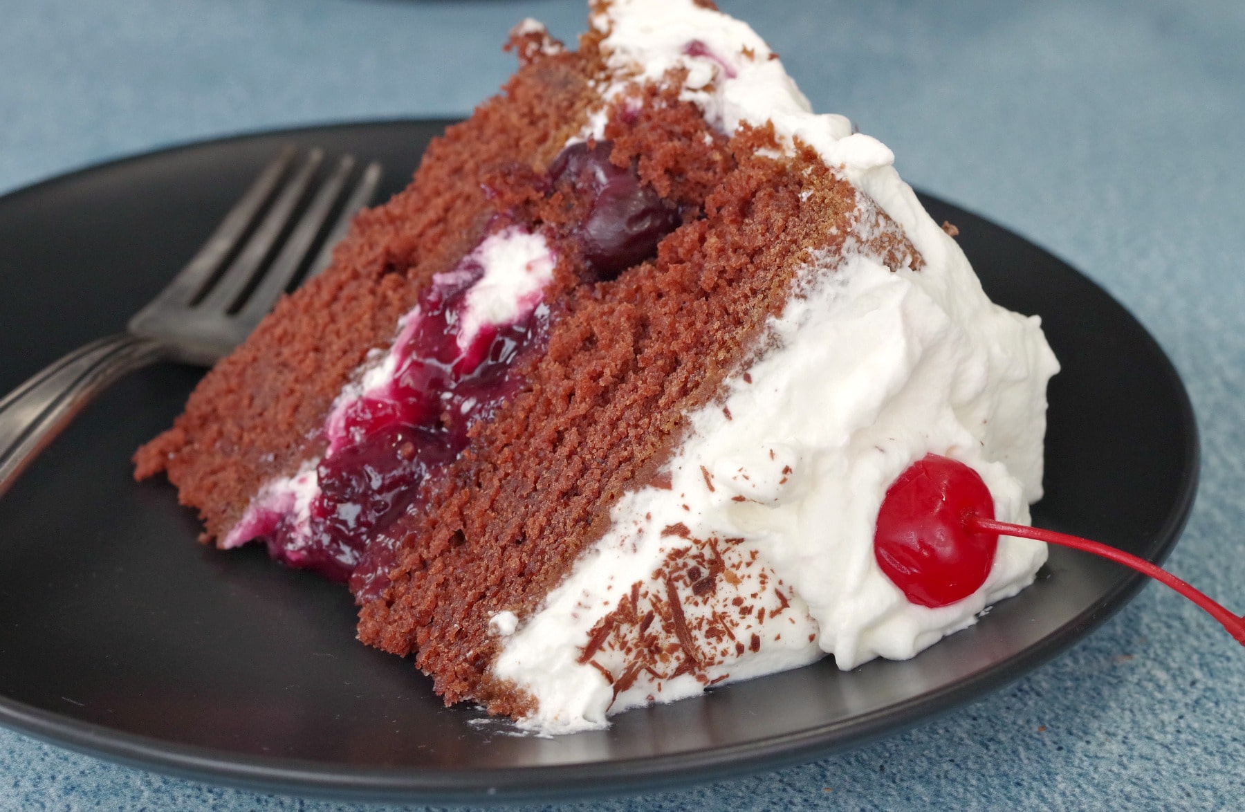 piece of black forest cake on black plate