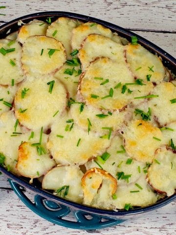 Potato casserole with spinach and beef in blue casserole dish