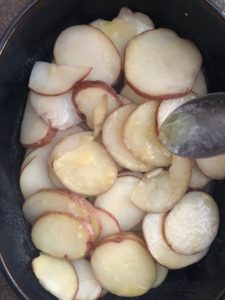 butter being drizzled on sliced potatoes