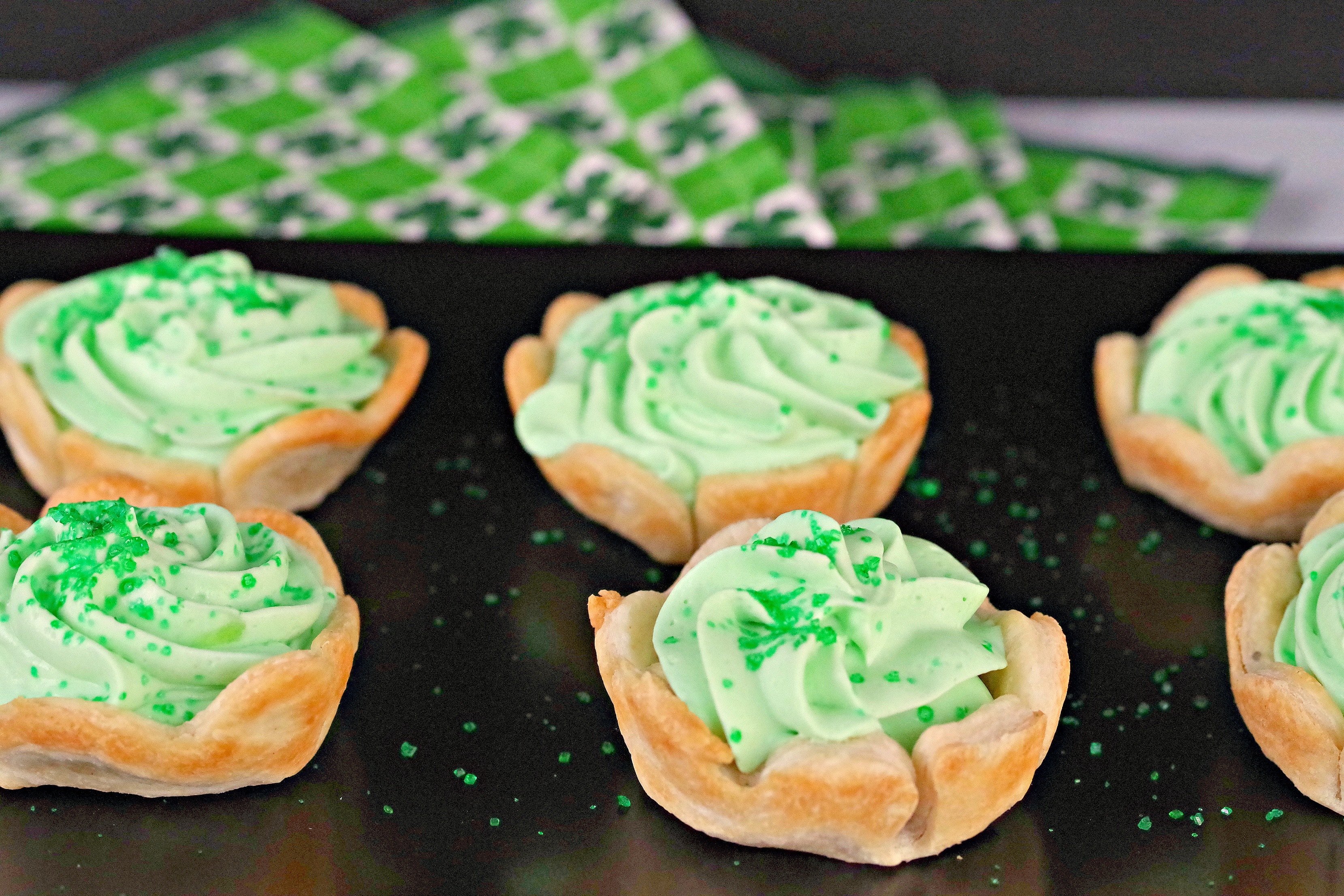 a tray of green Shamrock tarts on a black serving tray