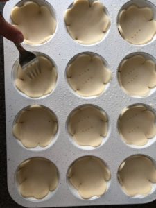 shamrock tart shells being placed in muffin tin, with fork pricking bottoms