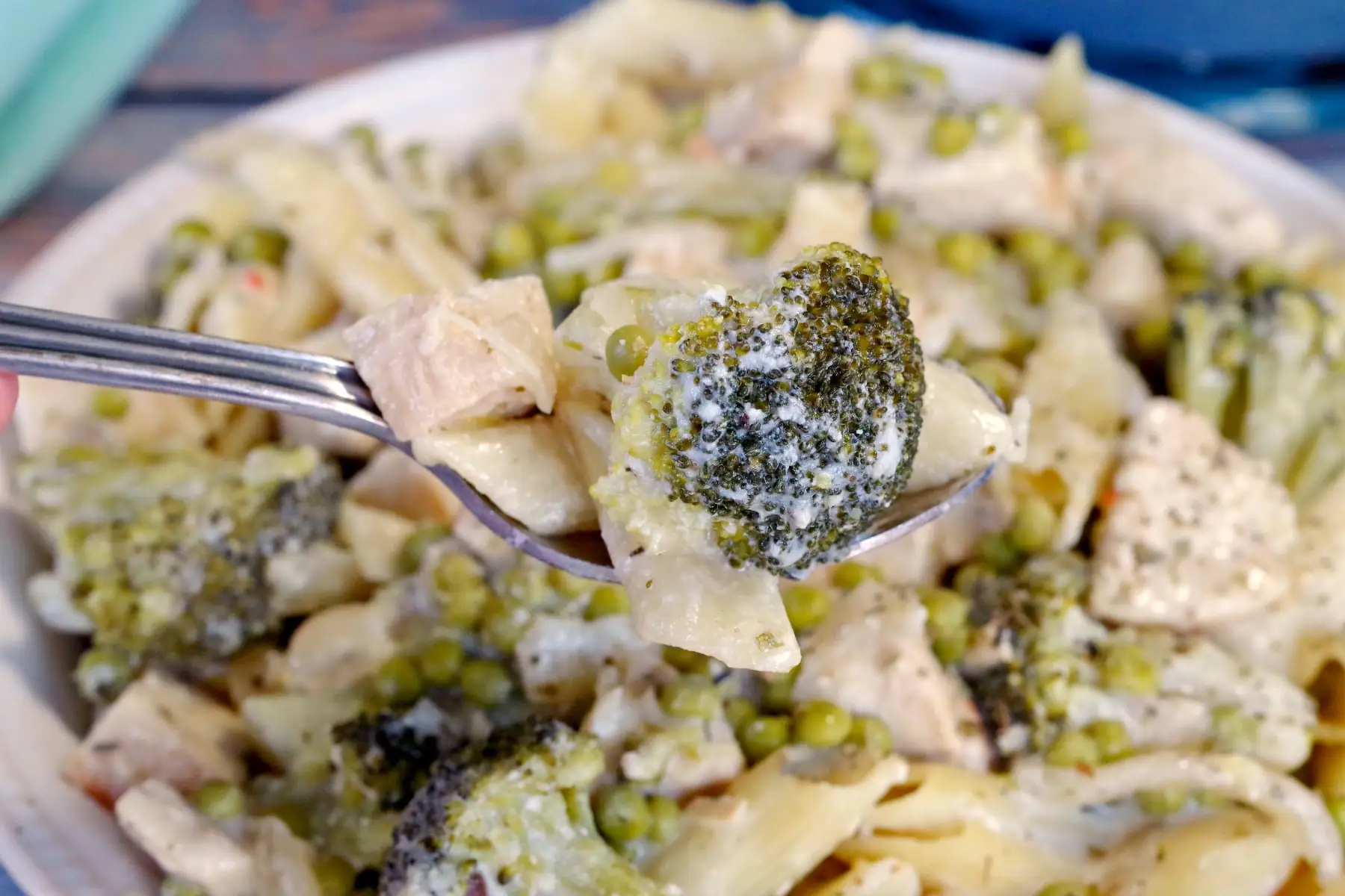 Cream Lemon Chicken pasta in a bowl with a spoonful being held up close to camera