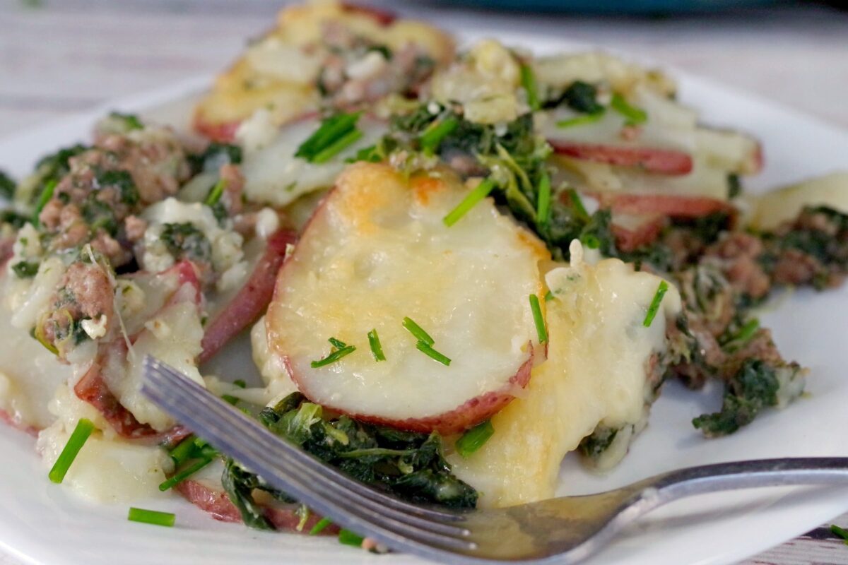 Close up of potato beef and spinach casserole on a white plate
