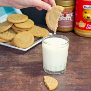 cookie butter cookie being dipped into a glass of milk