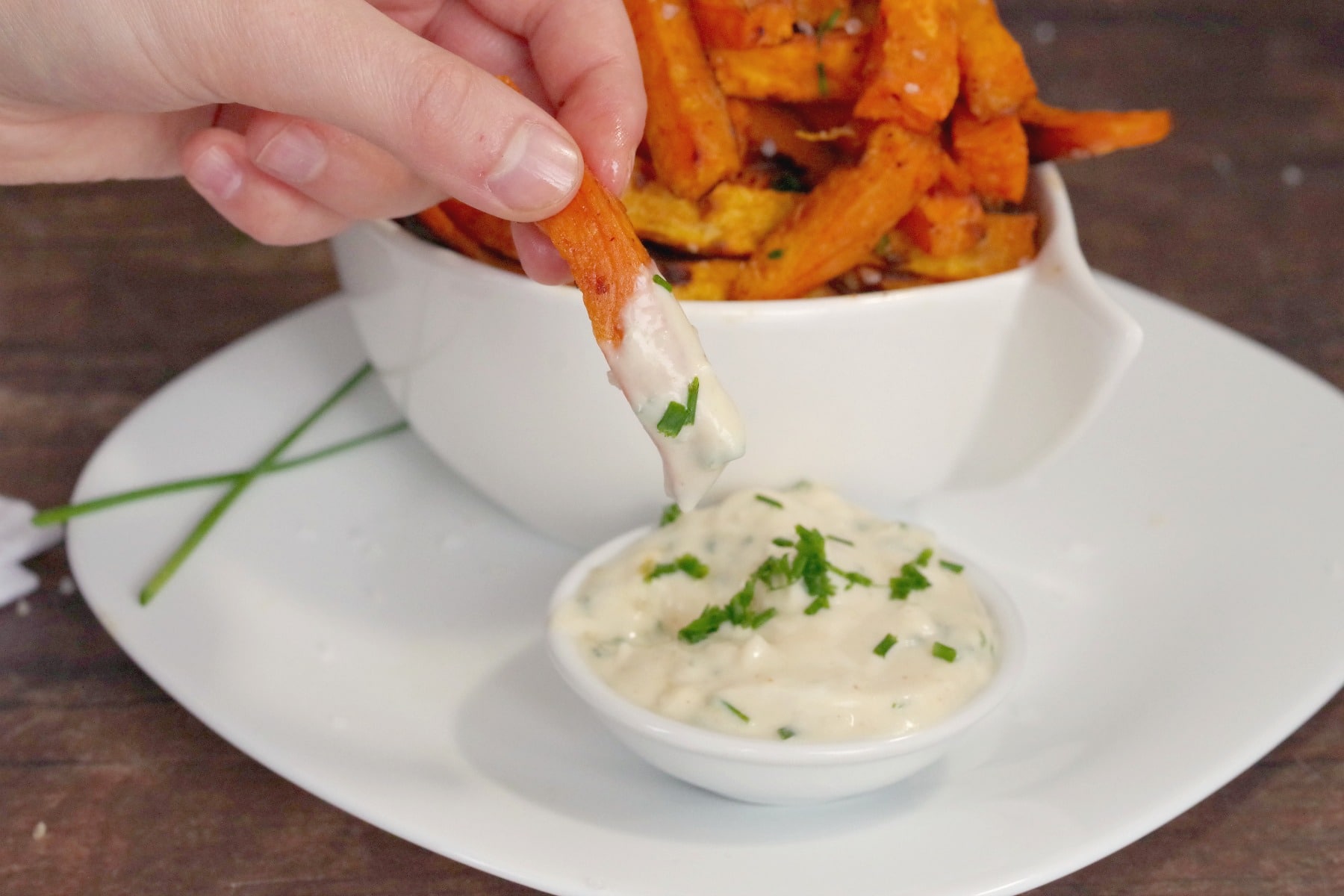 sweet potato fries being dipped into garlic mayo dip