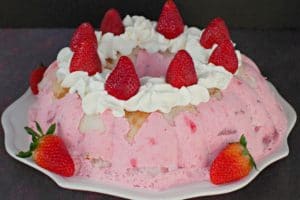 Whole strawberry jello angel food cake on white plate