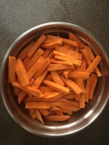 sweet potato fries tossed in bowl with oil and seasoning