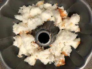 angel food cake torn into pieces in bottom of angel food cake pan