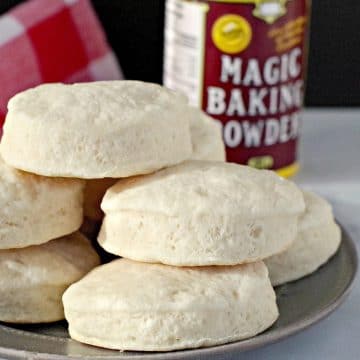 baking powder biscuits piled on a plate with magic baking powder in background