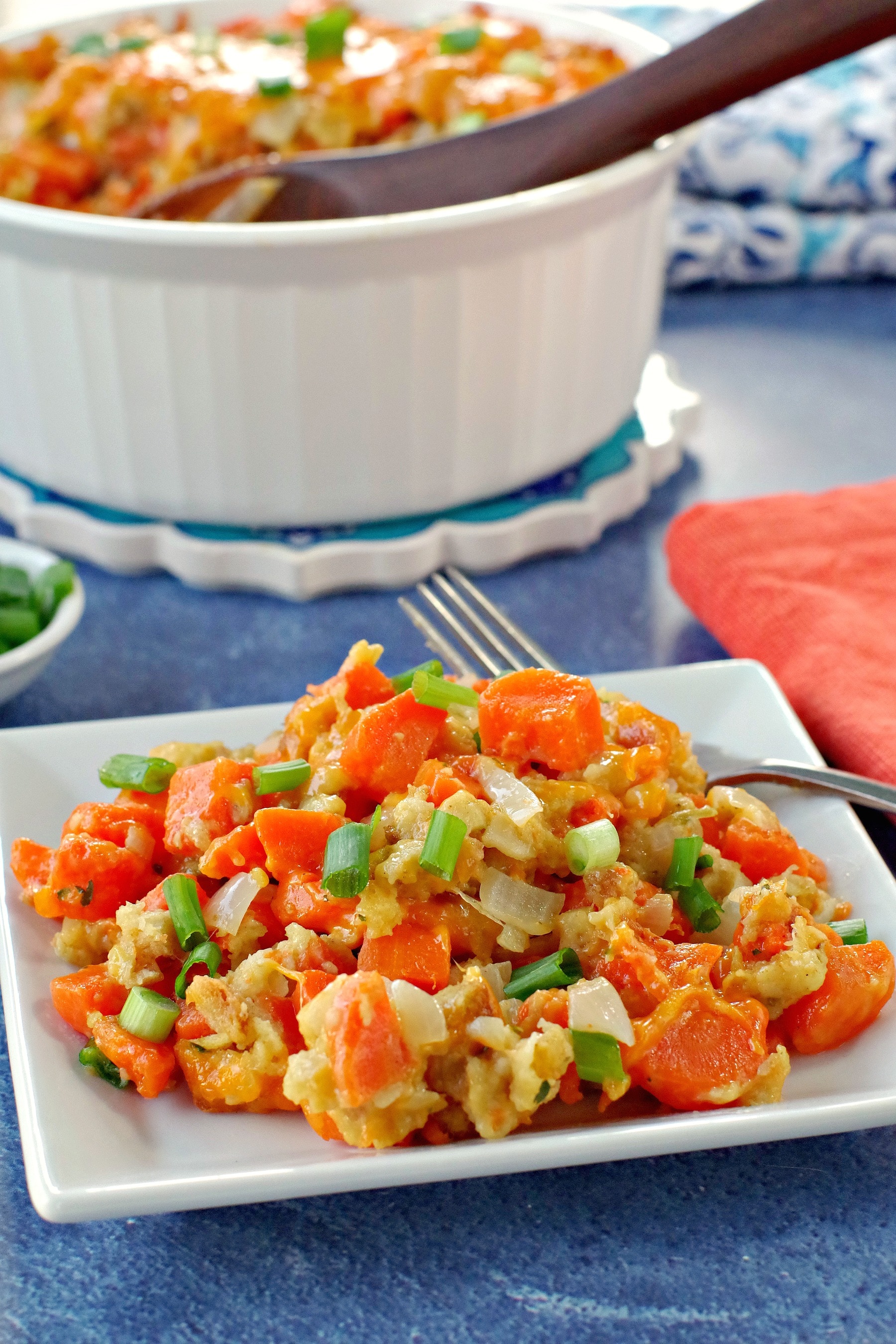 carrot casserole on white plate with white casserole dish full of carrot casserole in the background