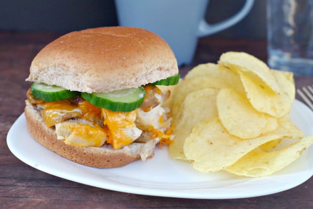 diced chicken breast burger on white plate with side of potato chips