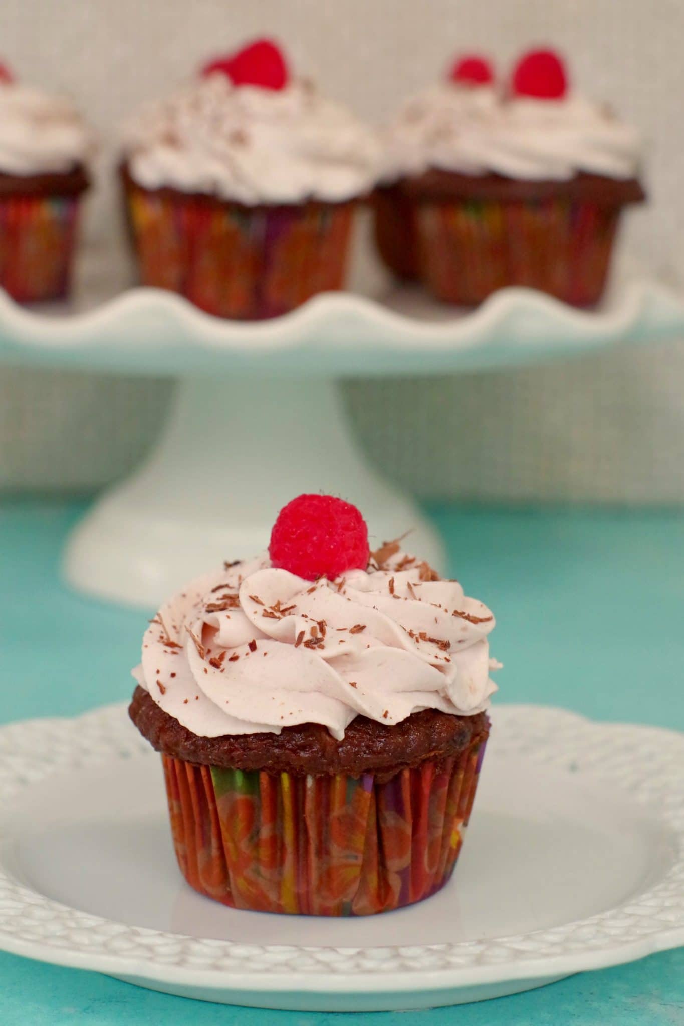 tiramisu cupcake on a white plate, with a white stand of cupcakes in the background