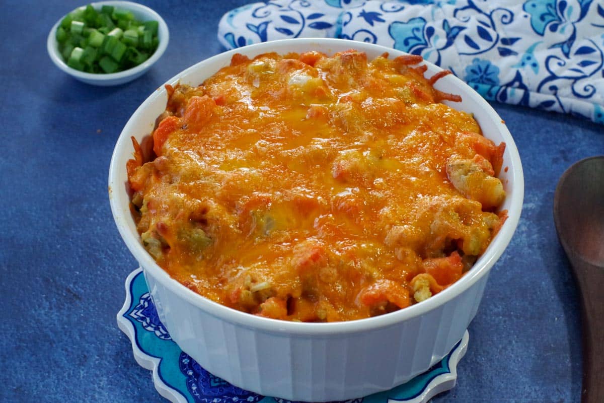 carrot casserole with melted cheese on top in white casserole dish