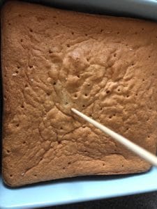poking holes in top of cake with skewer