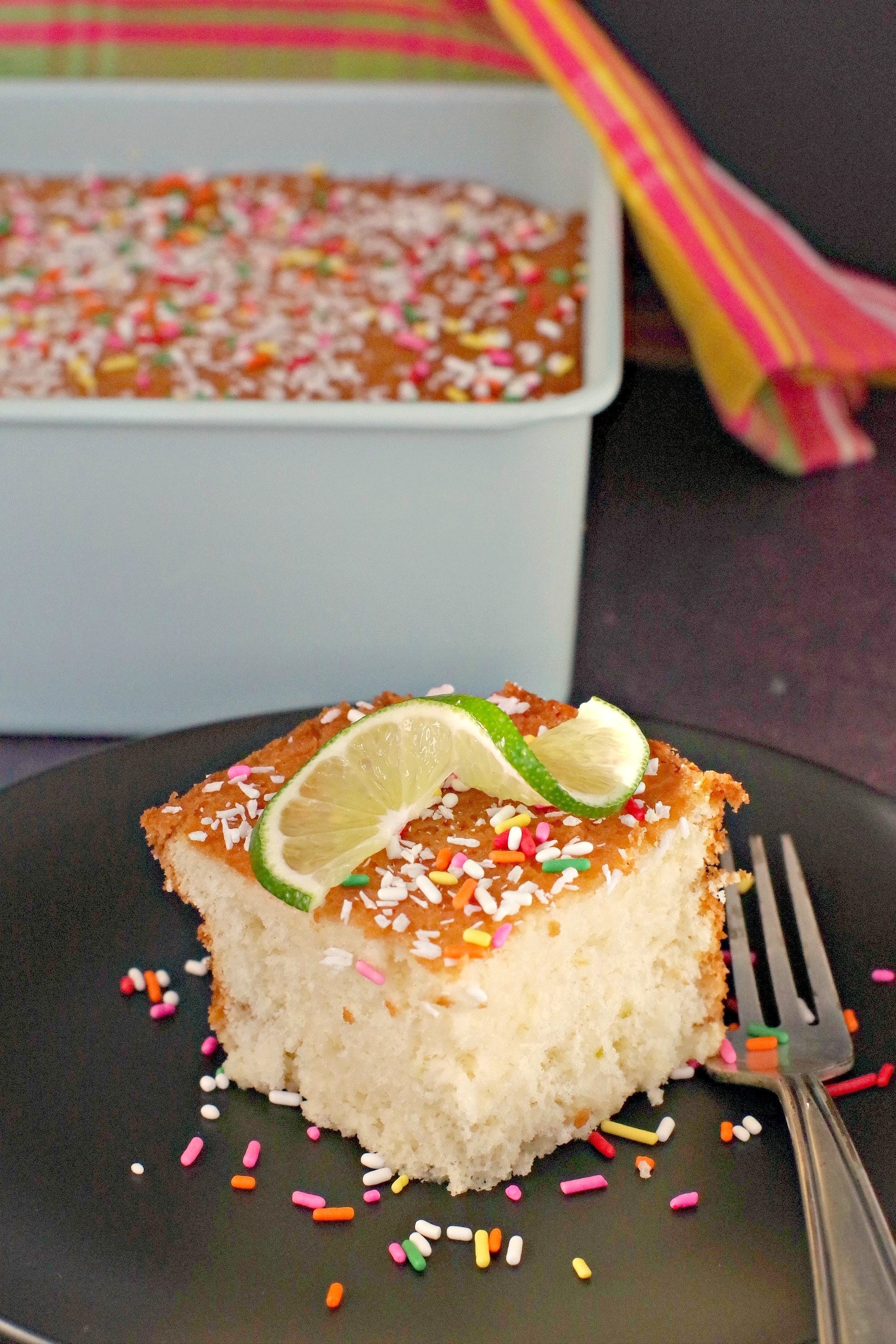 tres leche cake on plate with cake pan behind