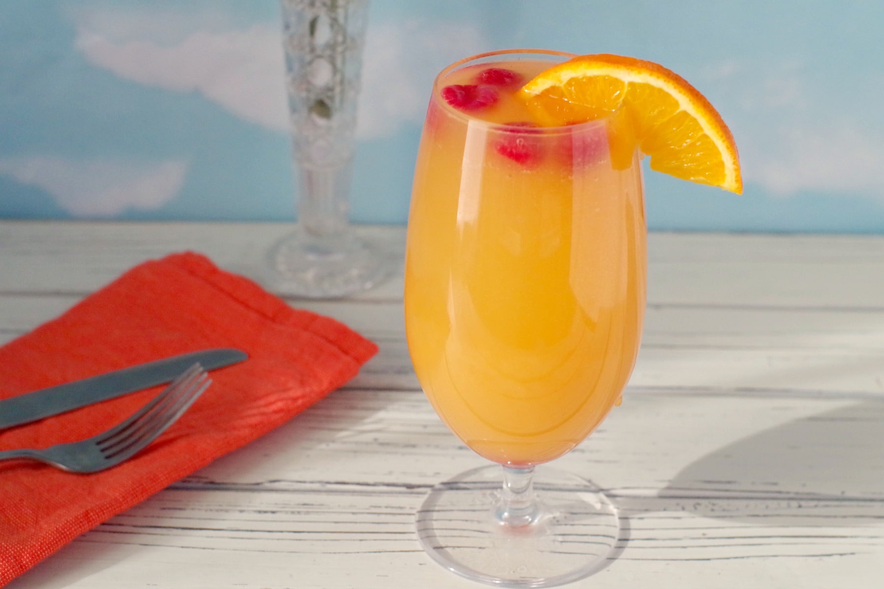 mimosa drink with raspberries and orange garnish