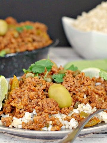 Picadillo over rice with rice and pan of picadillo in background