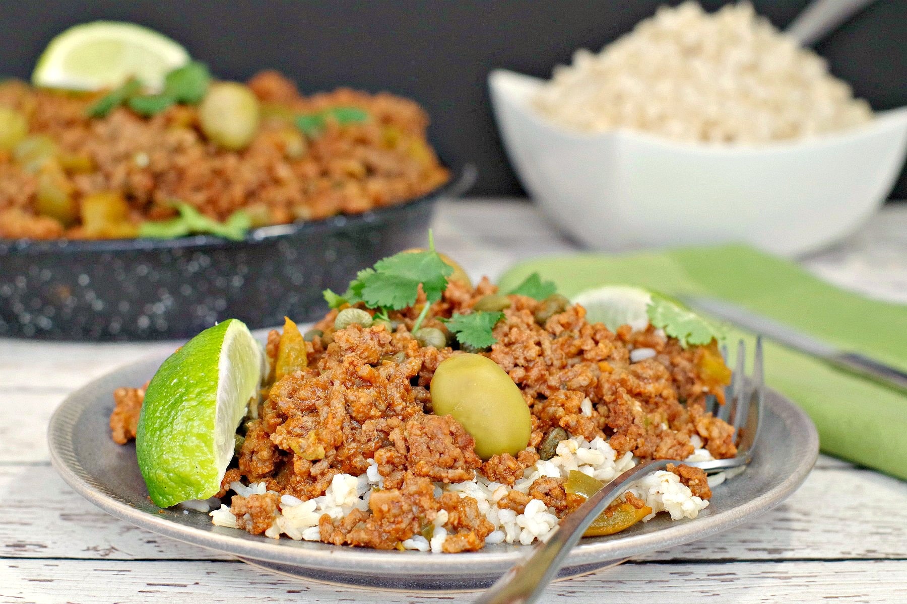 Picadillo over rice with rice and pan of picadillo in background