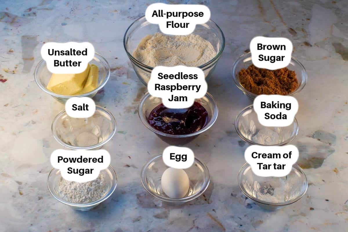 Ingredients in raspberry jam cookies in glass bowls, labelled.