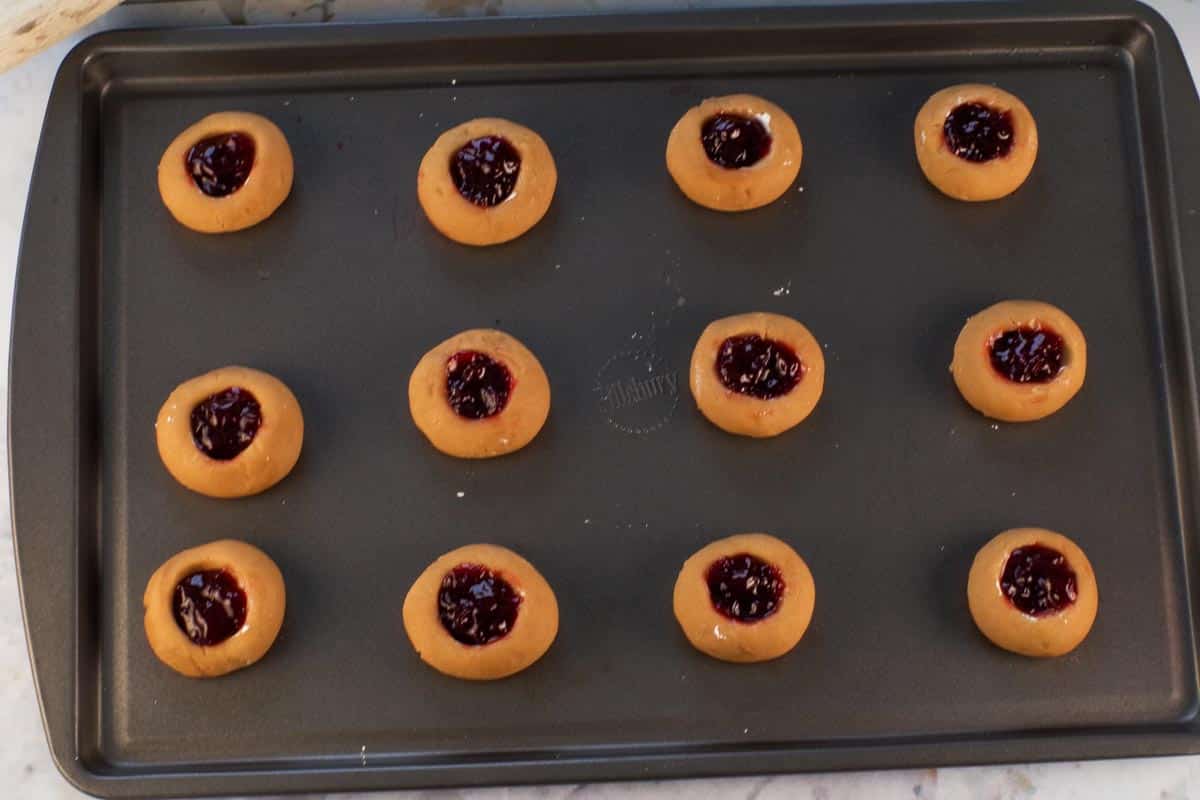 Jam inside cookies ready to go into oven on a baking sheet.