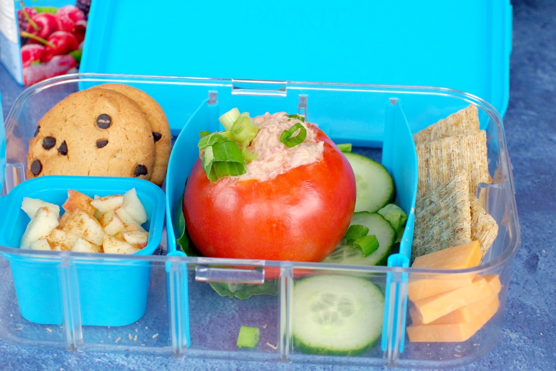 stuffed tomatoes in lunch box with cracker, cheese, cookies and apple yogurt