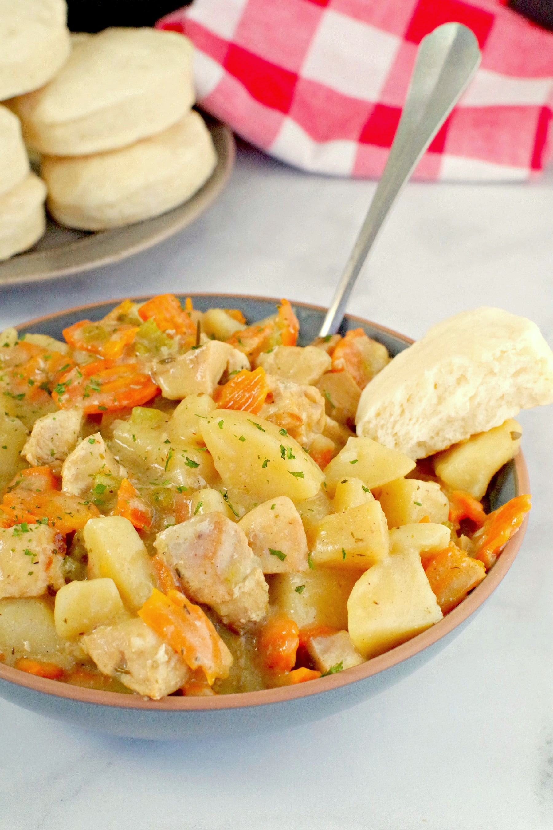 slow cooker chicken stew in blue bowl with biscuit on the side