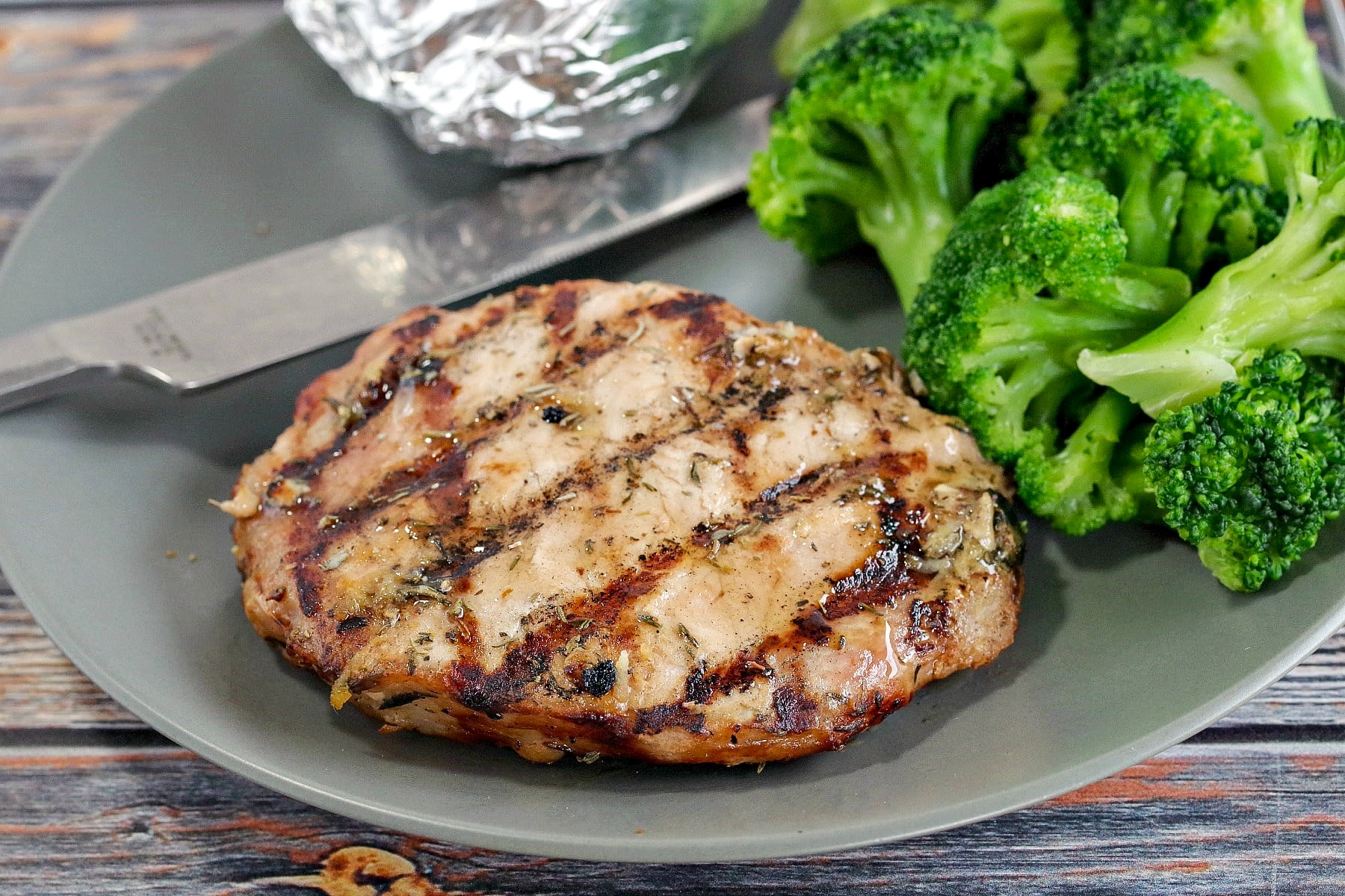 Maple lemon pork on a plate with broccoli and baked potato in foil