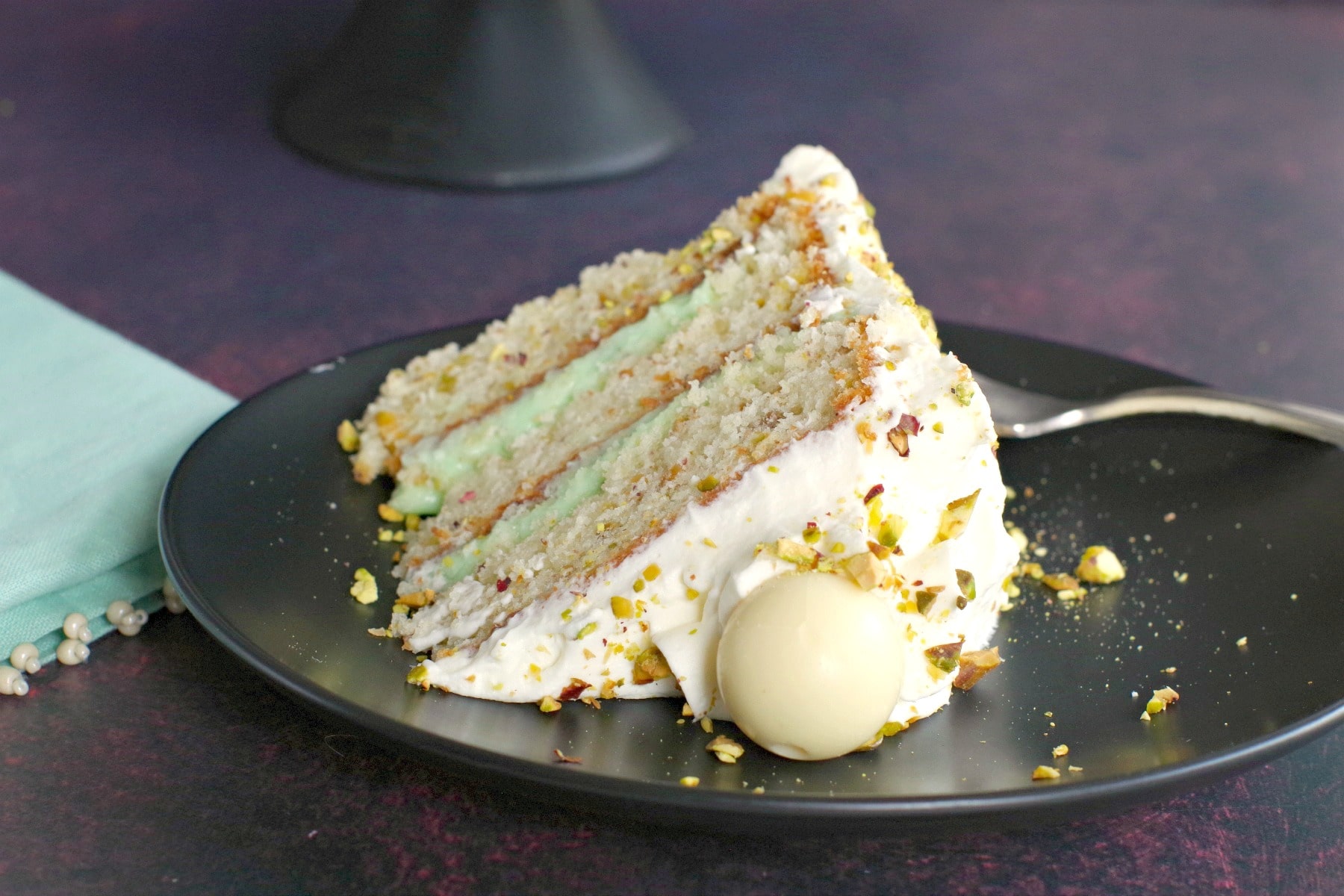 Piece of White Chocolate Pistachio Cake on black plate